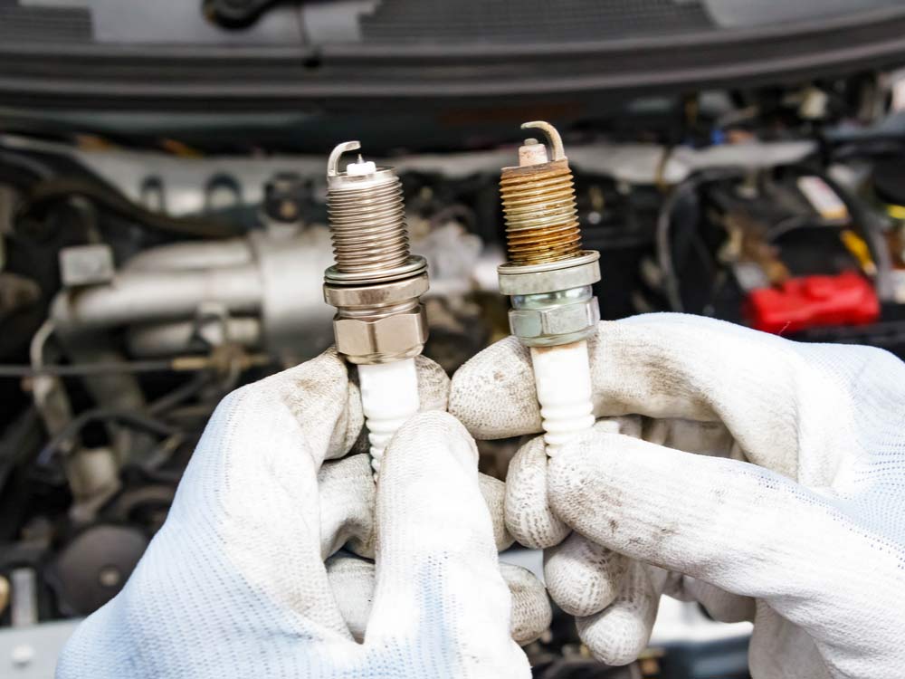 a mechanic comparing two spark plugs