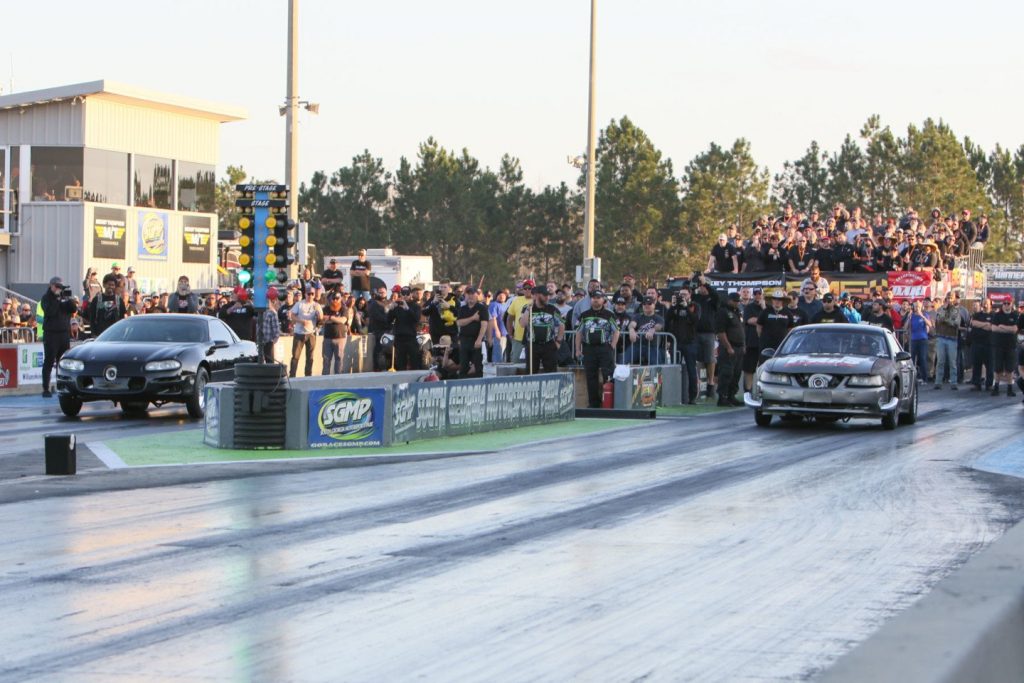 a pair of cars launch at a drag strip