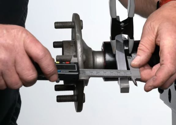man measuring axle standoff with a dial caliper