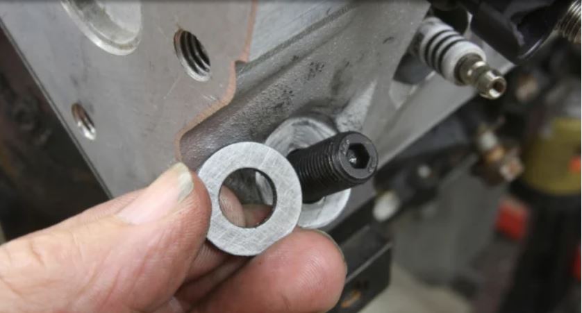 man holding washer shim for engine cylinder head bolt studs