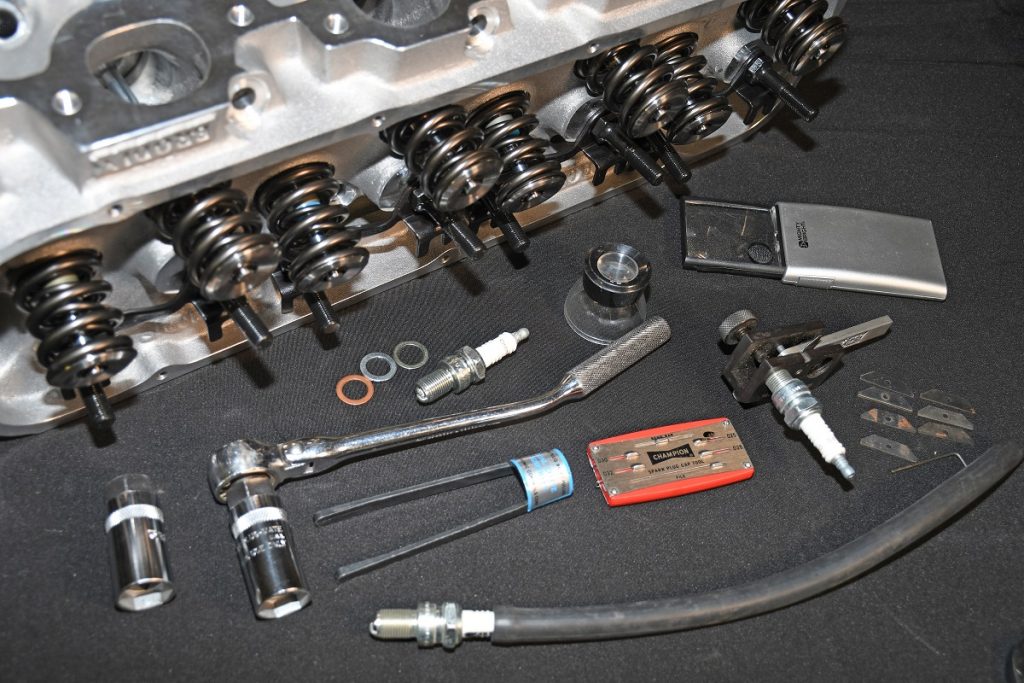 a cylinder head laying alongside a collection of spark plug tools