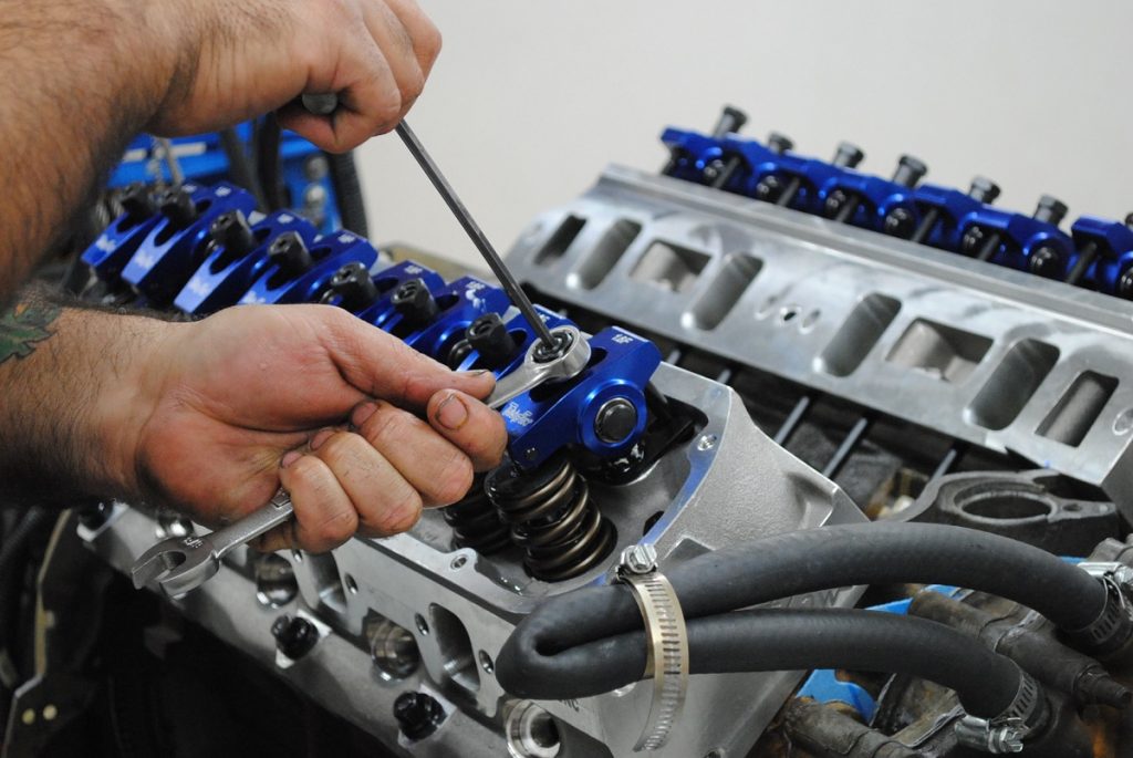 man adjusting rocker arm valve lash on a ford 5.0 liter v8 engine