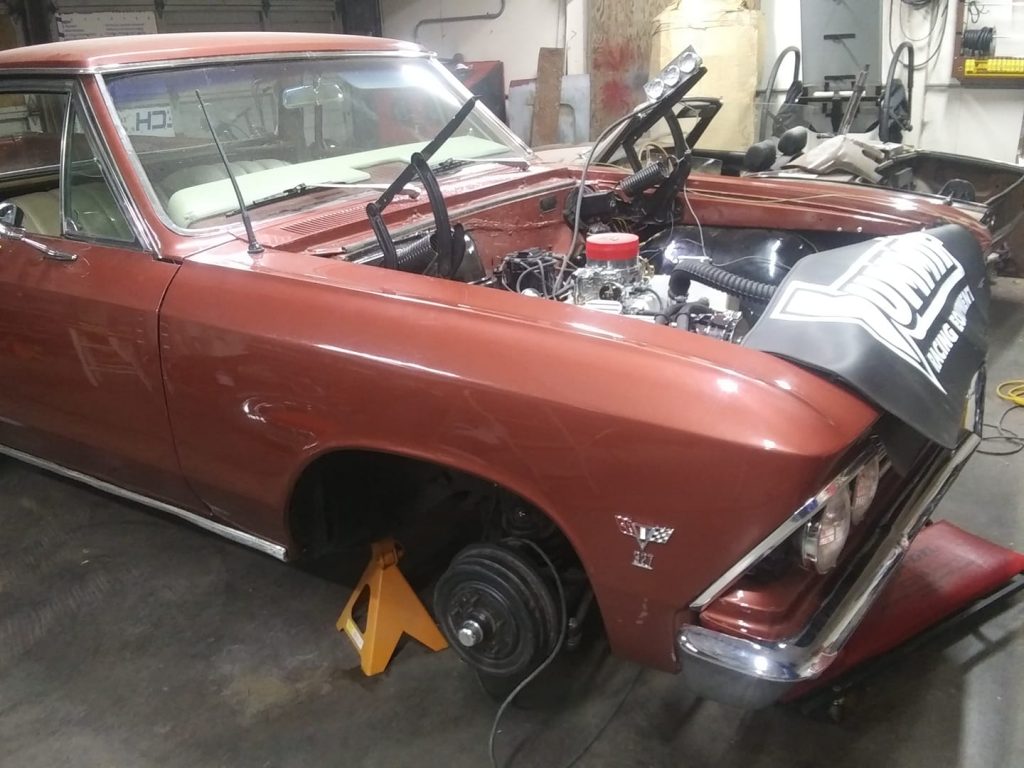 front end of first gen chevy chevelle in garage for service with hood removed