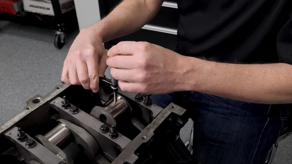 man measuring and checking rod bearing clearance on an engine crankshaft