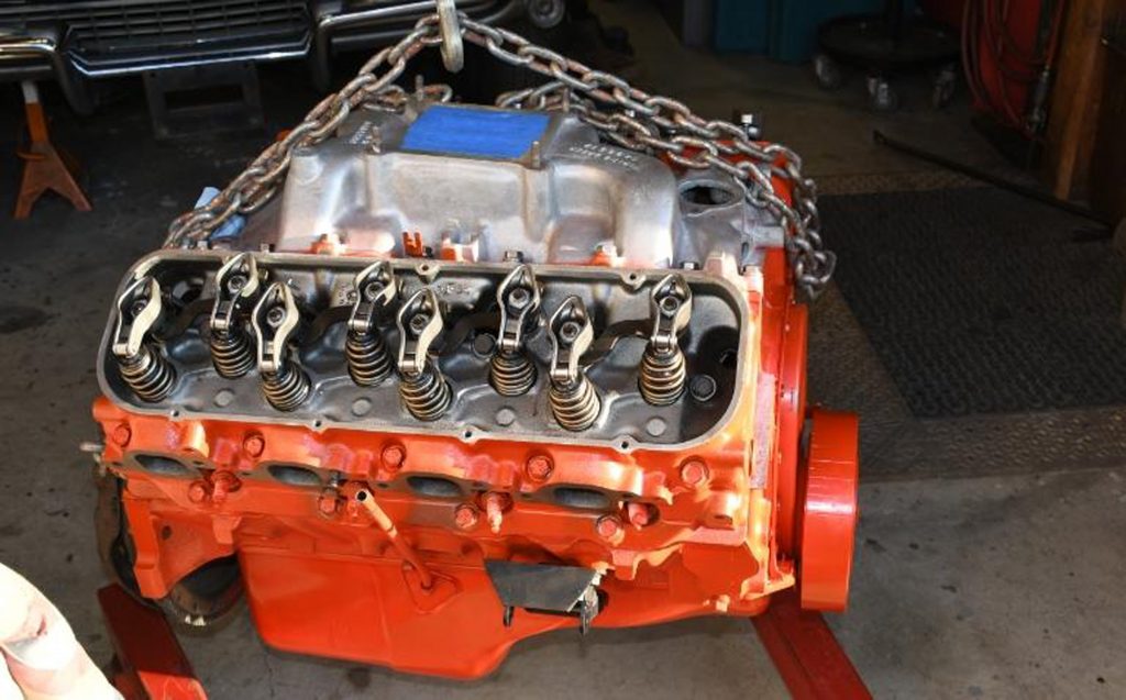 big block chevy hanging from an engine hoist with valve covers removed