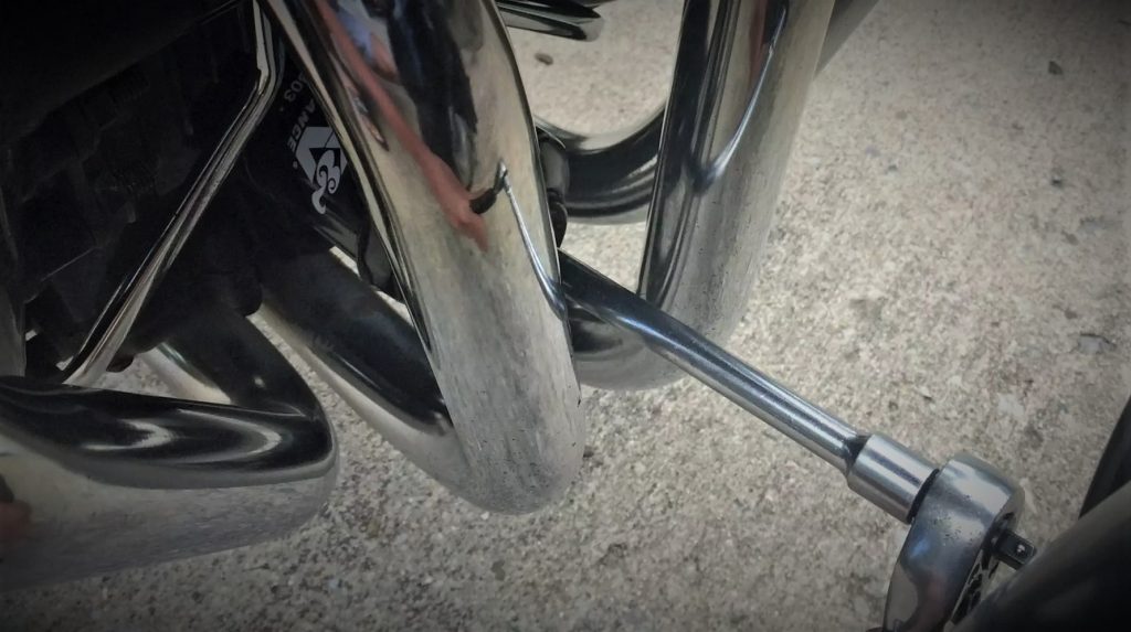 a socket extension being used to remove an oil fitler behind mototcycle headers