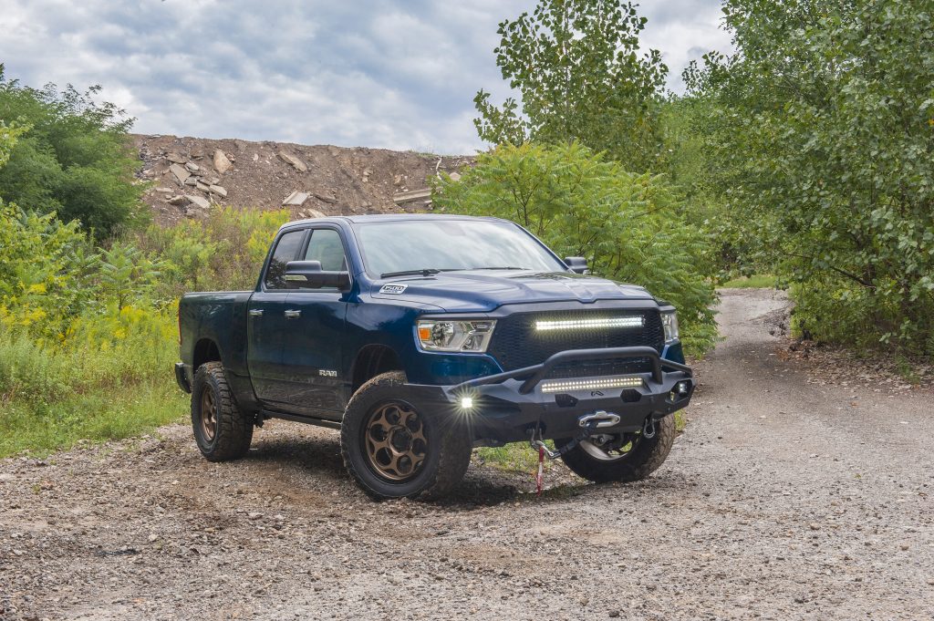 2020 ram big horn 1500 with off road upgrades and wheels on wooded dirt trail