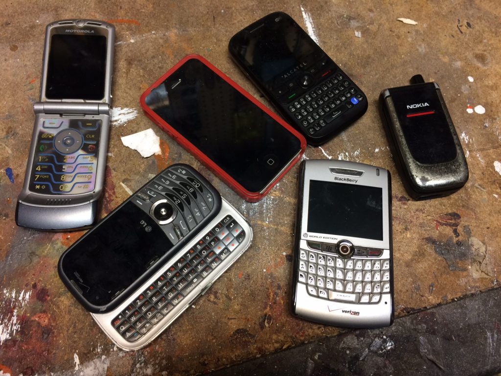 collection of old cell phones on a workbench