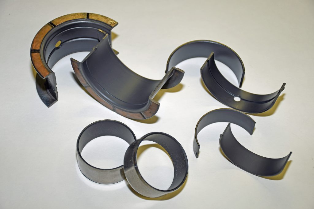 assorted engine bearings scattered on a white surface