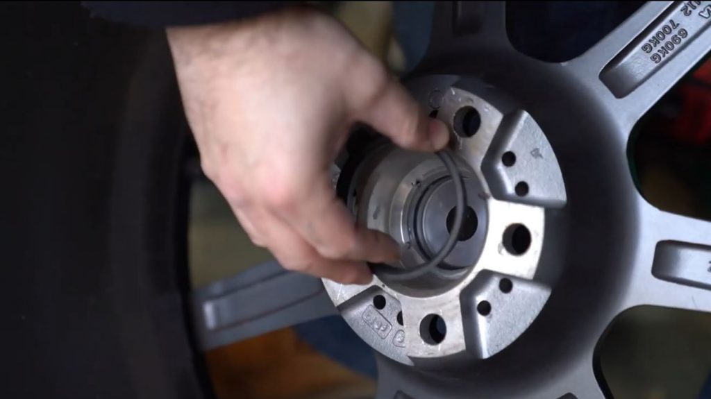 man installing a hubcentric ring into an aftermarket wheel