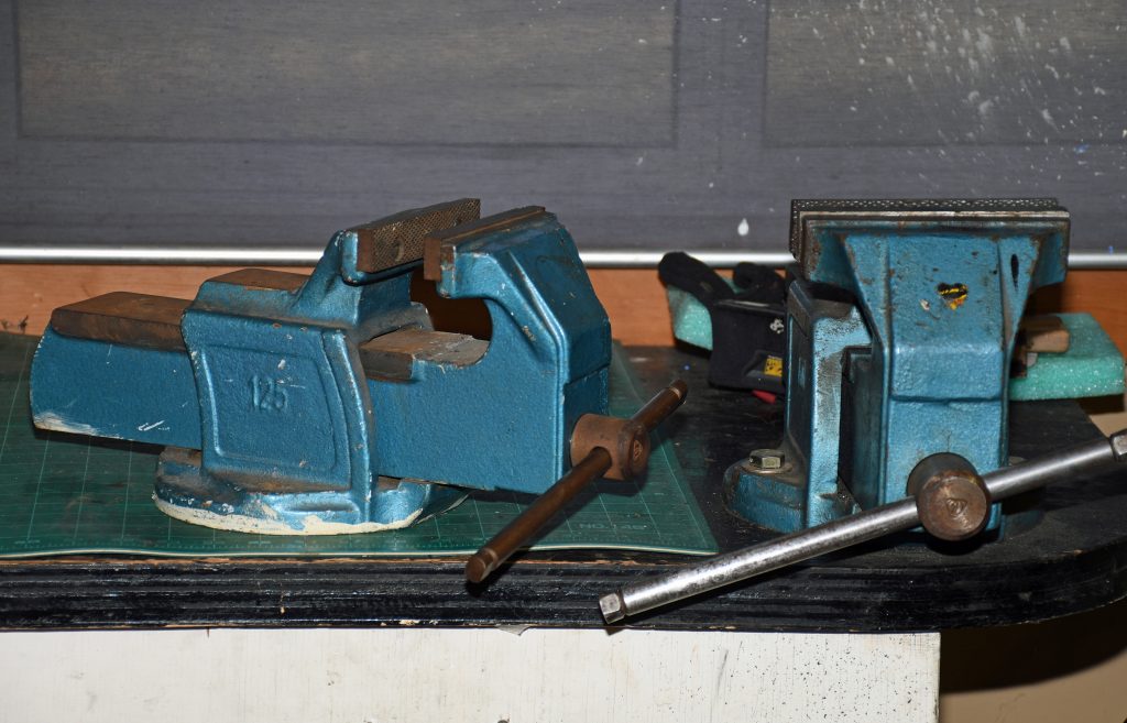 a pair of vintage bench vises on a workbench