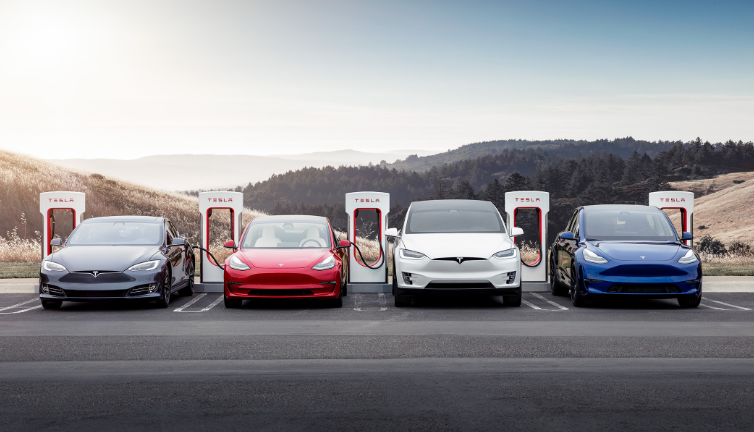 row of tesla cars hooked up to a tesla supercharger station