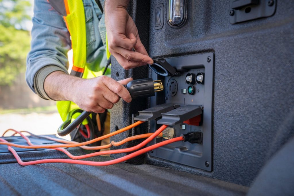 man plugging in electrical devices into ford f-150 bed