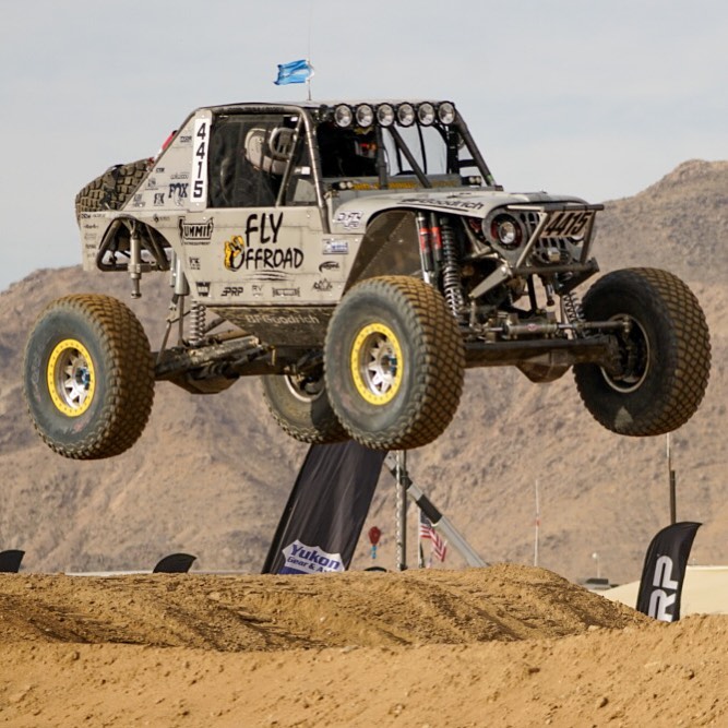 ultra4 off-road race buggy truck launching over a dirt hill during king of the hammers race