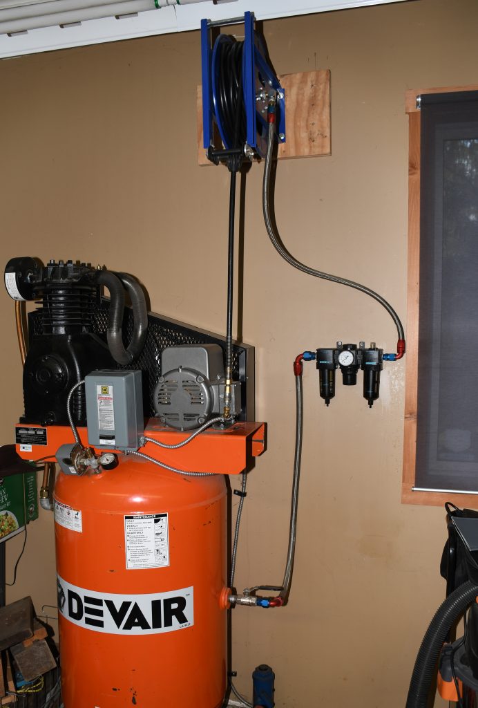 shop air compressor with hoses and regulators installed in a home garage