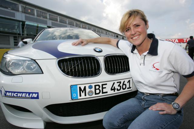 sabine schmitz poses with bmw race car