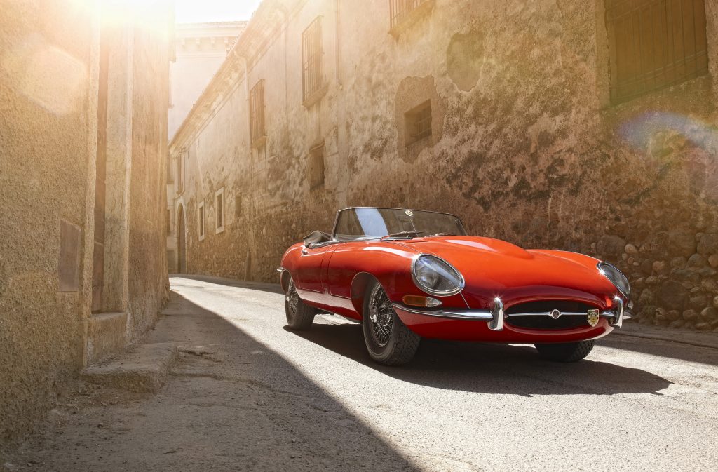 red jague xke e type parked in narrow European town road