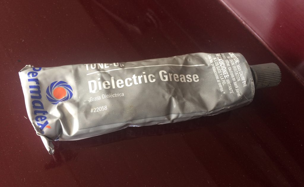 a tube of dielectric grease resting on the hood of a car