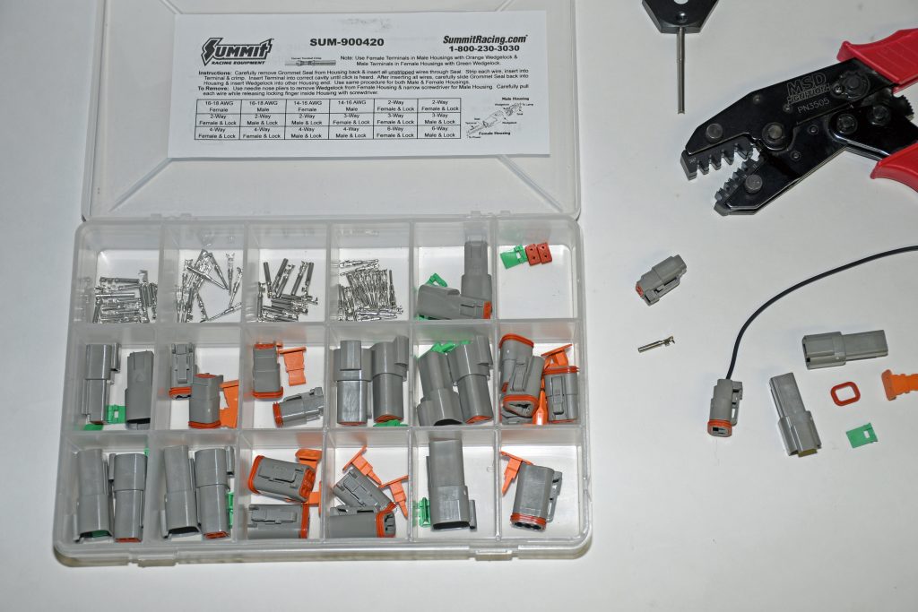 collection of weatherproof deutsch connectors, assembly tools, and parts on a white tabletop