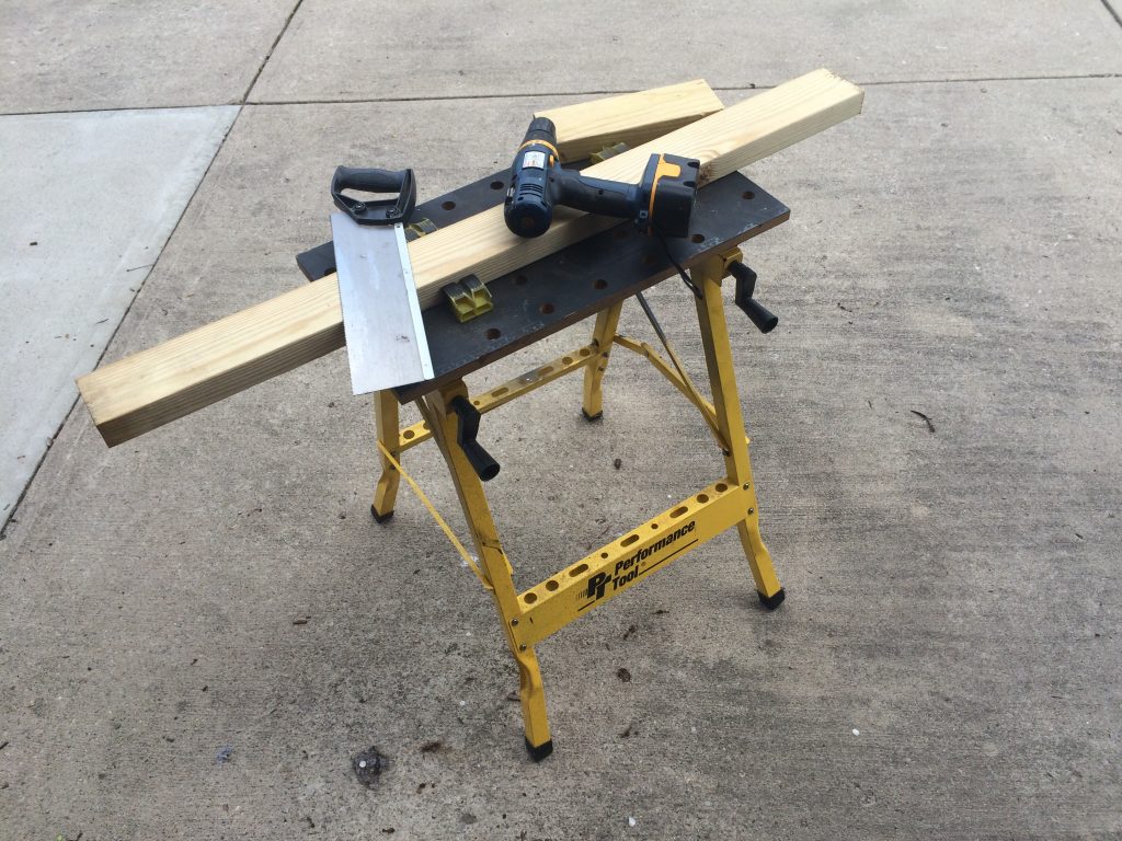 a performance tool folding workbench with saw, drill, and wood clamped in place