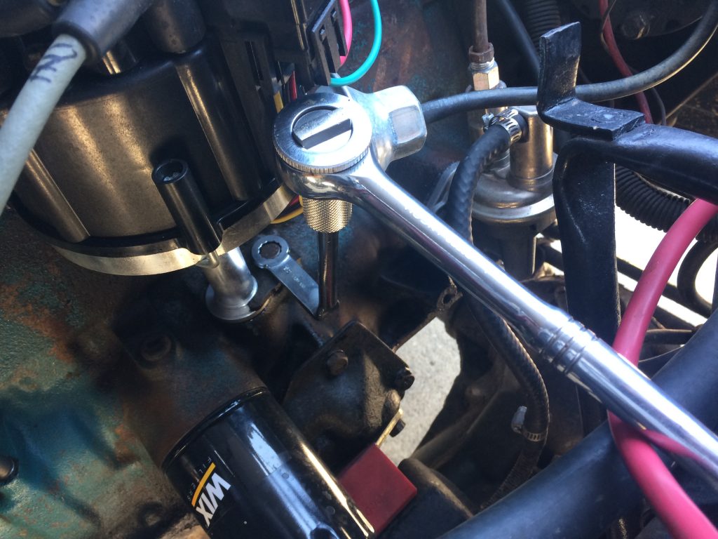 distributor clamp wrench being used to loosen clamp bolt on an amc 258 engine