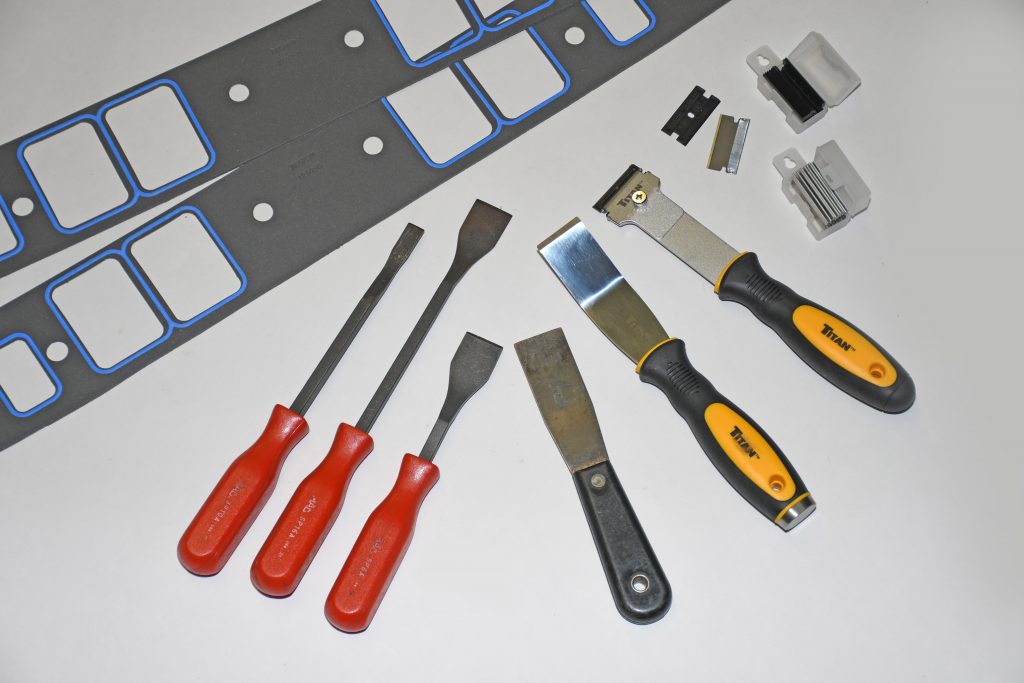 colleciton of gasket scraping tools and header gaskets on a white background