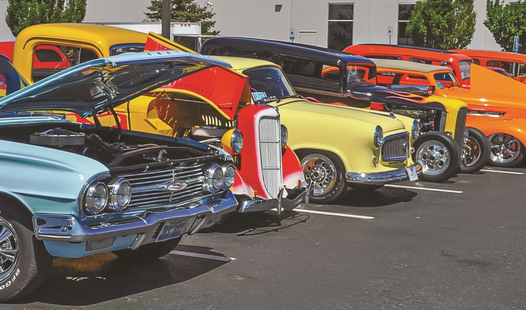 row of classic cars and hotrods at a car show