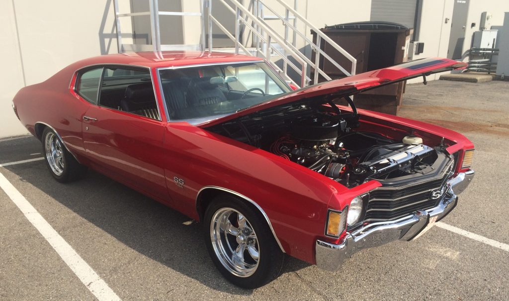 red chevy chevelle ss at a car show with aftermarket wheels