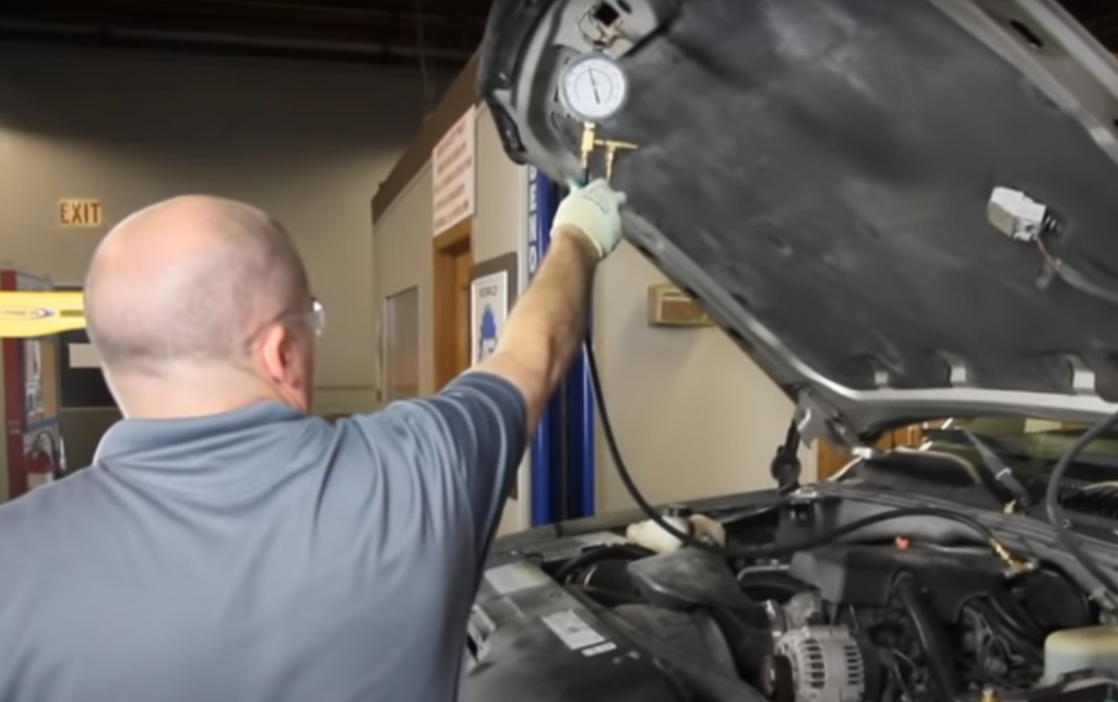 man using a gauge to measure a car's fuel pressure