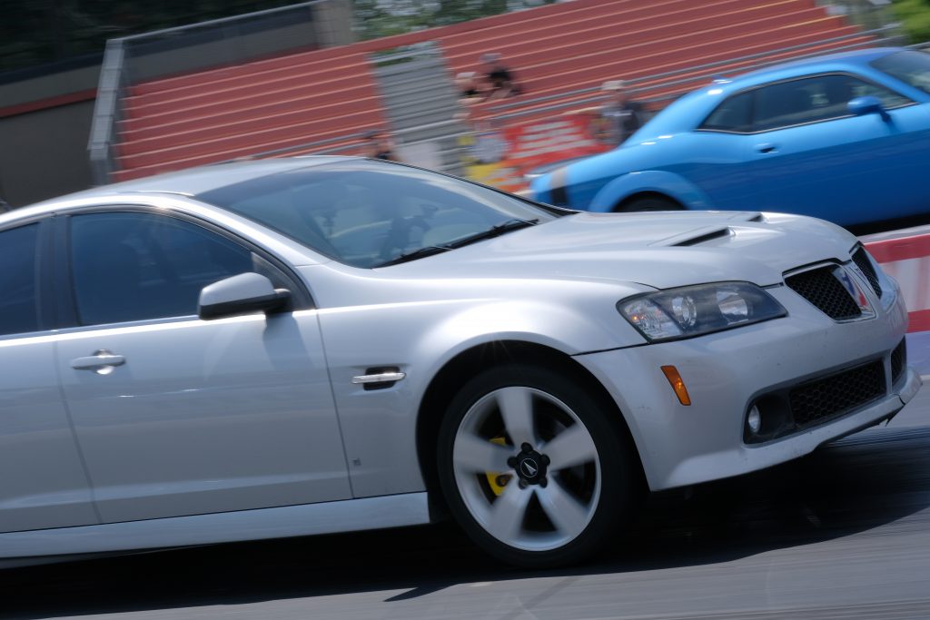 silver pontiac g8 and blue dodge challenger racing at a drag strip