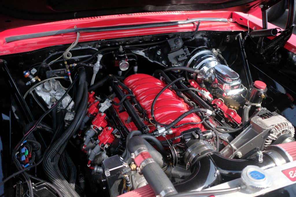 ls engine in a vintage muscle car with red painted air intake manifold