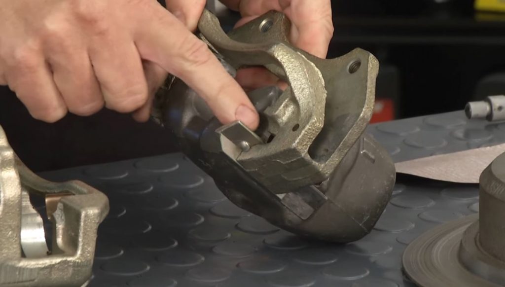 man pointing to lubrication point in a disc brake caliper