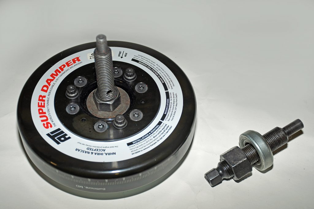 a harmonic balancer and installation bolt tool sitting on a workbench