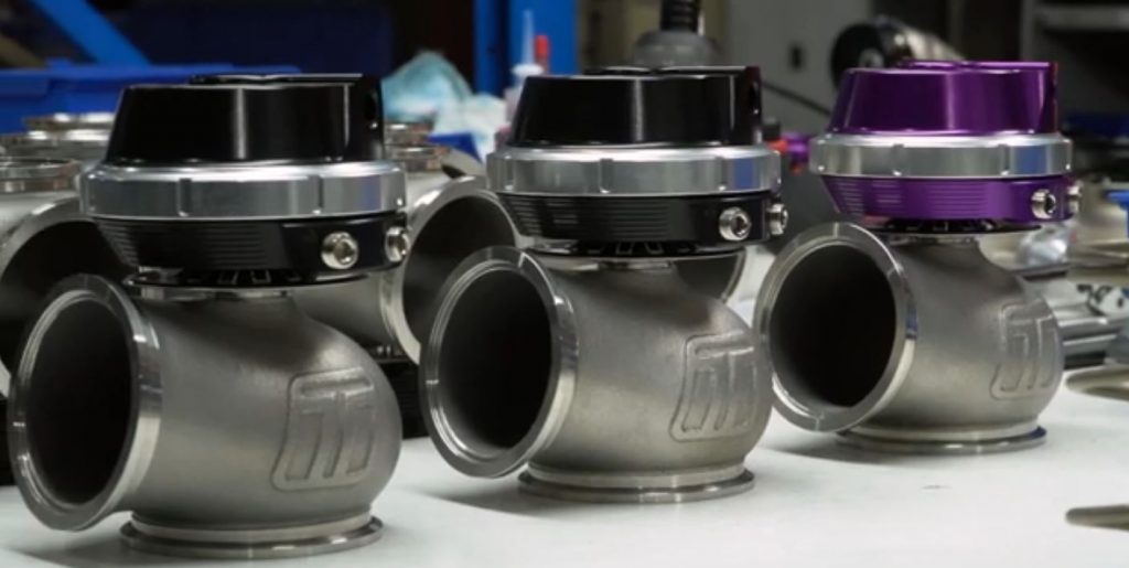 row of turbosmart wastegates on a table at a car event
