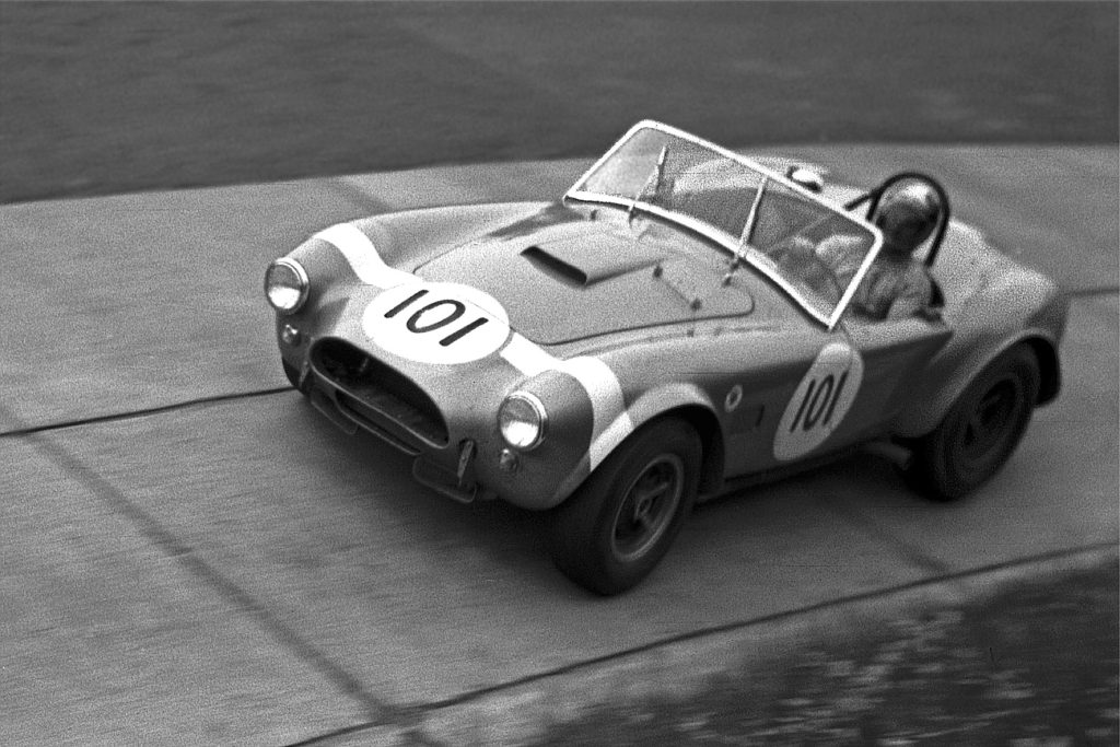 vintage photo of bob bondurant driving an ac cobra around a racetrack in 1964