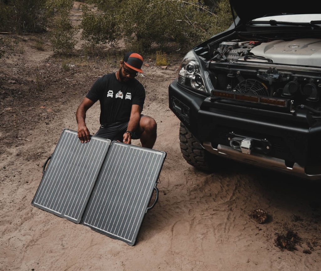 man unfolding redarc solar panels at his overlanding campsite
