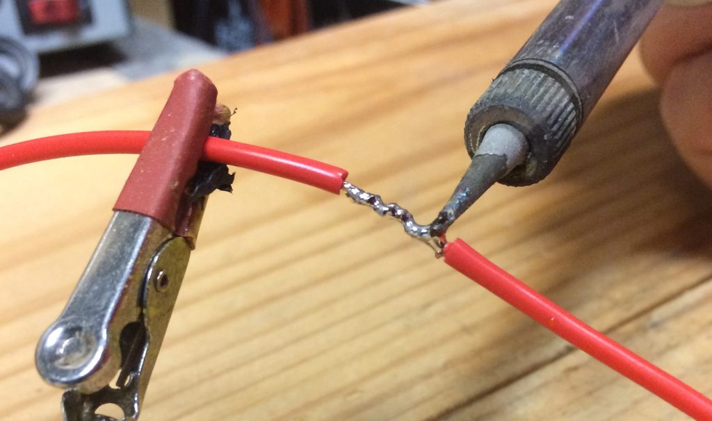 a soldering iron melting solder into a lienman's splice to repair an electrical connection on wire