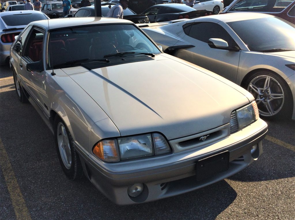 silver foxbody ford mustang at a car show