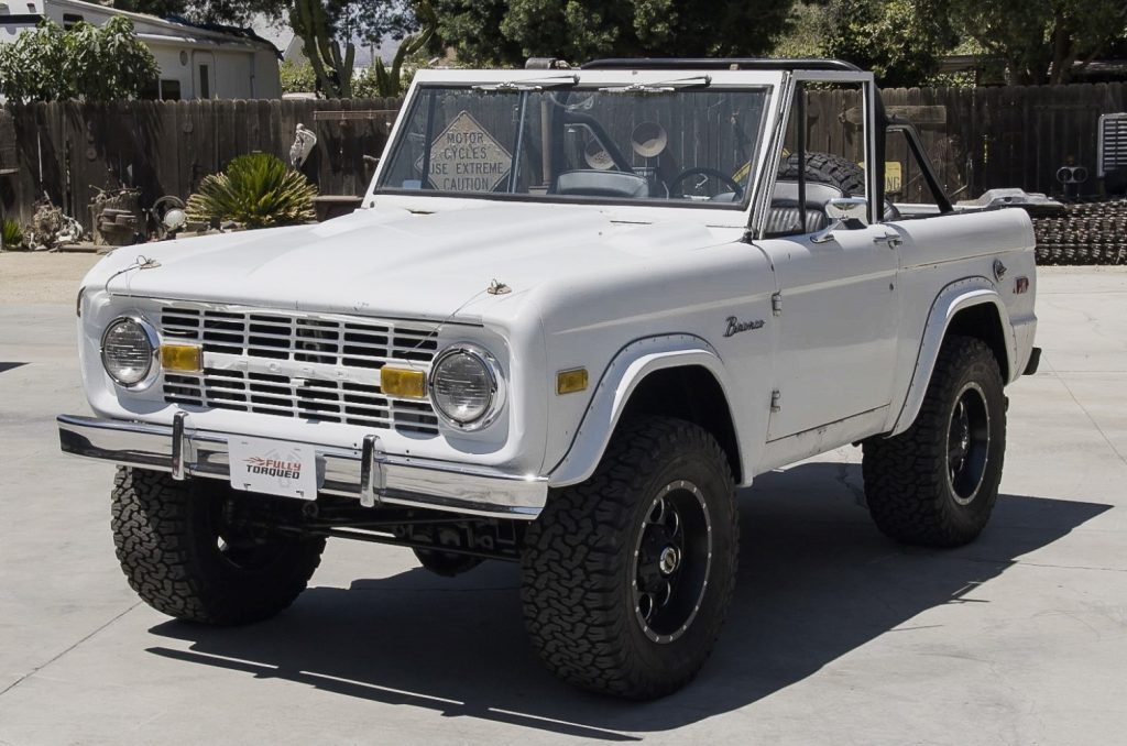 driver side quarter shot of white 1974 ford bronco with top removed