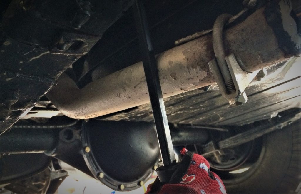 using a lrage metal pry bar to align exhaust components under a car
