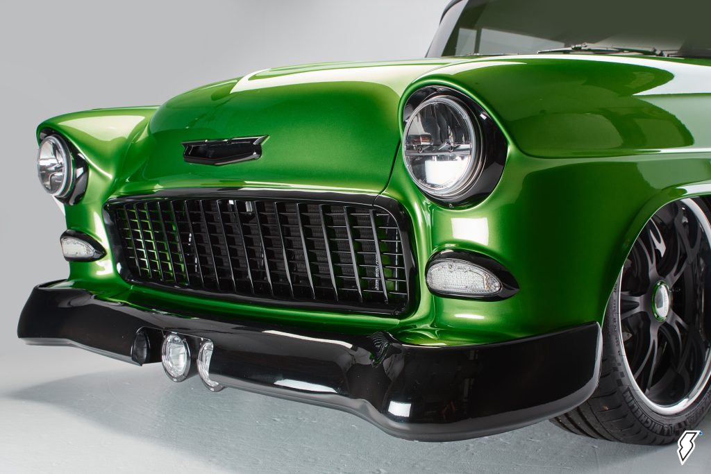 front grille and bumper shot of wildly customized 1955 chevy bel air black on green