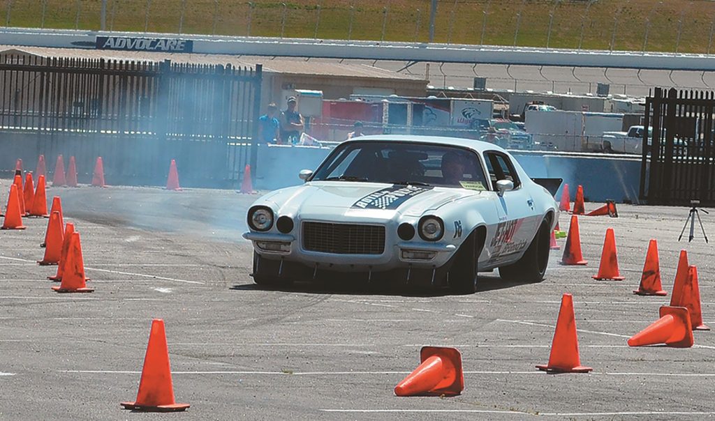 vintage chevy camaro accelerates with tire smoke through cones on an autocross track