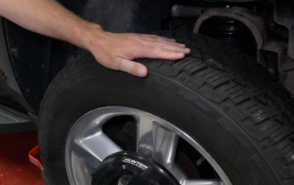 man's hand on top of a car tire