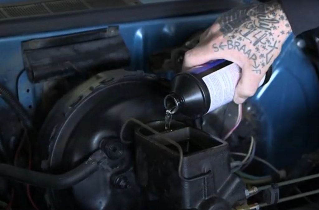 man pouring brake fluid into car's master cylinder reservoir