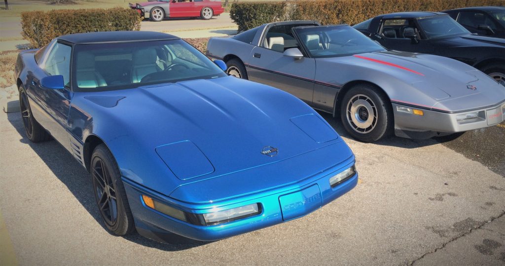 pair of c4 corvettes one blue one silver at classic car show