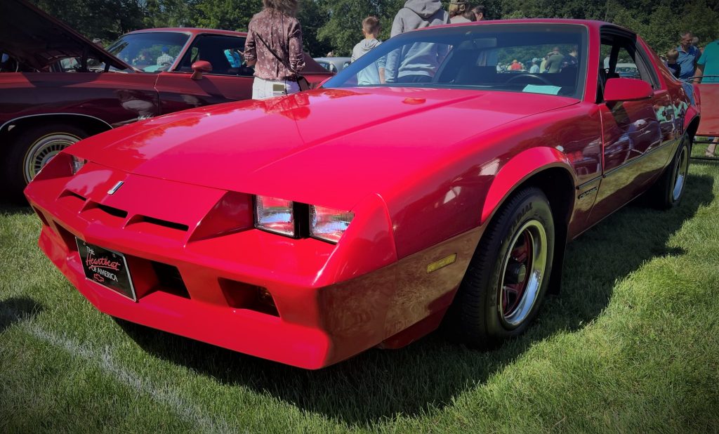 red third generation chevy camaro at a car show