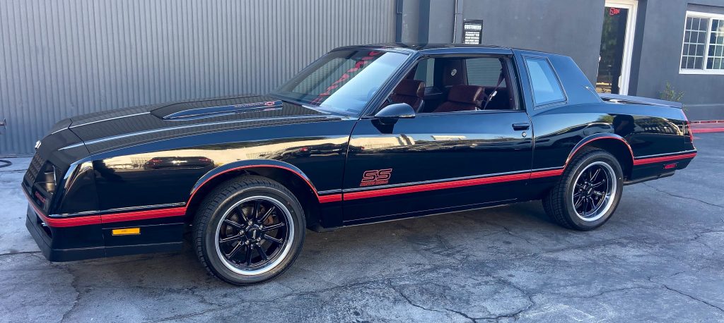a mid-1980s chevy monte carlo ss, black with red stripes