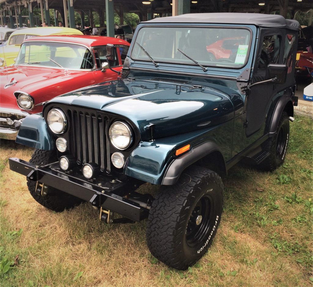 a dark green jeep cj-5 with a soft top at a classic car show