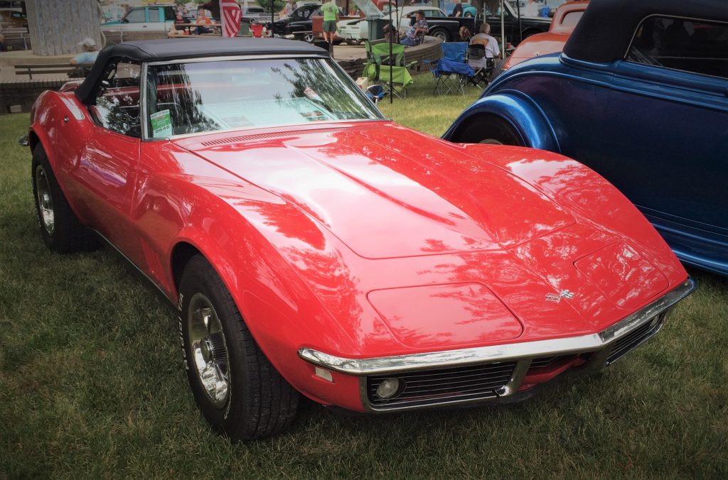 front view of a red 1968 chevy corvette convertible with a black ragtop at a car show