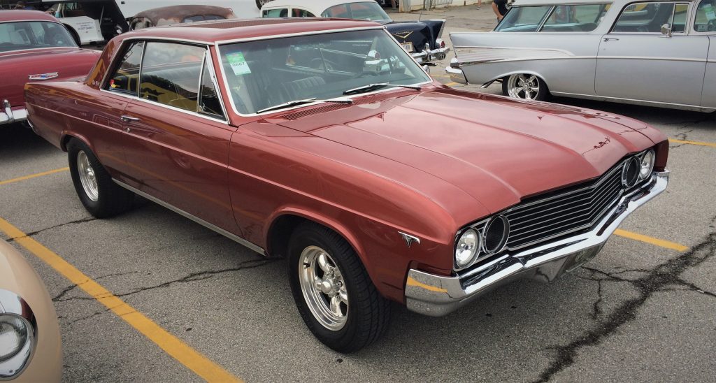 red 1964 buick skylark parked at a car show
